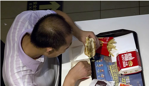 중국 베이징의 맥도날드 매장에서 한 남성이 햄버거를 먹고 있다.
